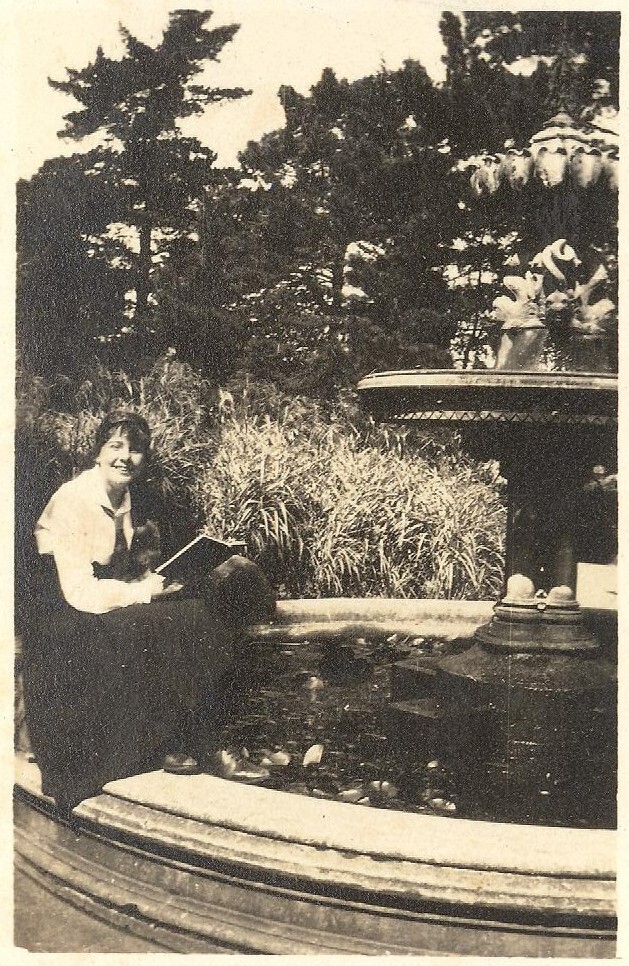 Photo of friend of Winnie Woodmason holding book, at fountain, c.1917
