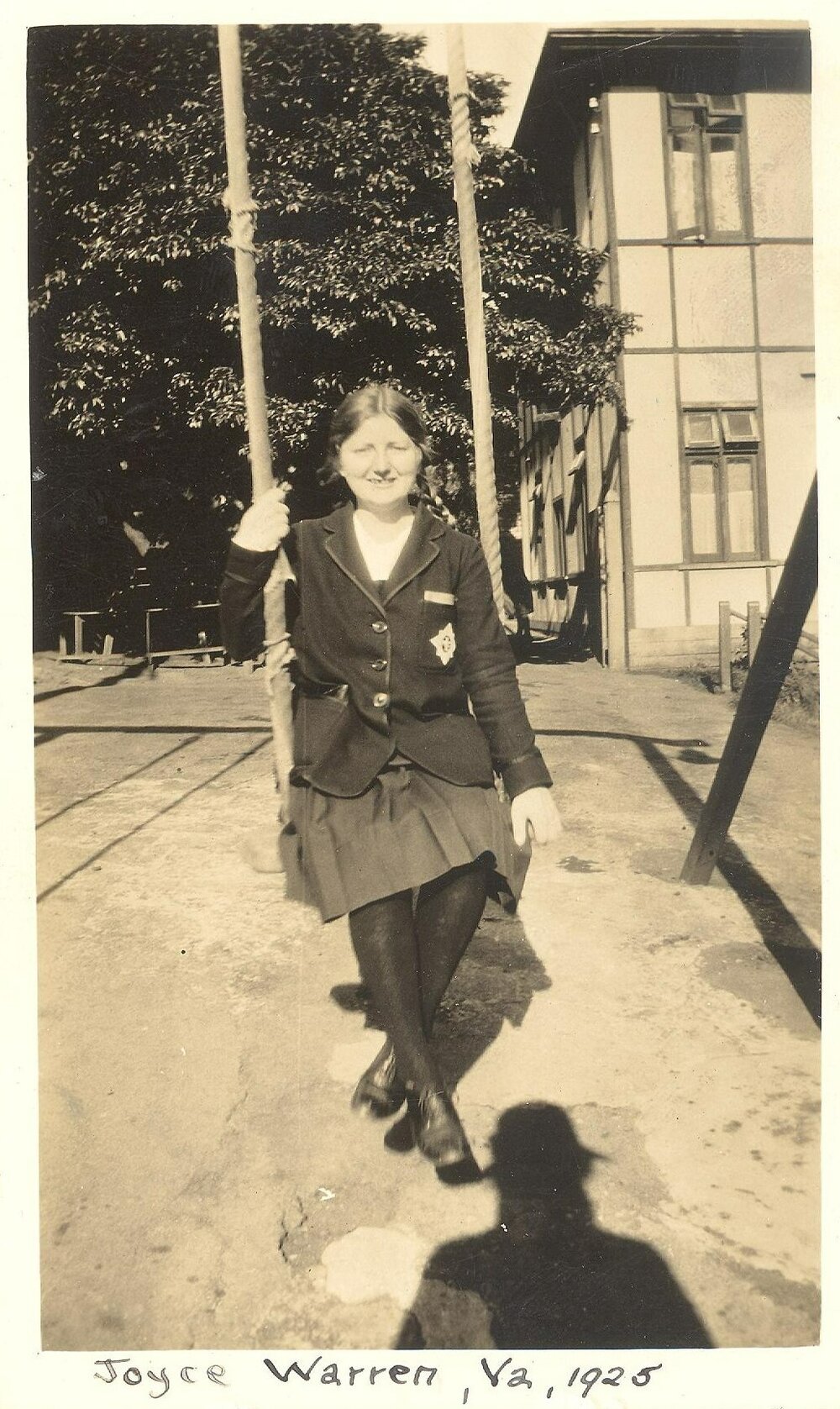 Photo of student Joyce Warren on swing, Hostel or North House in background, 1925