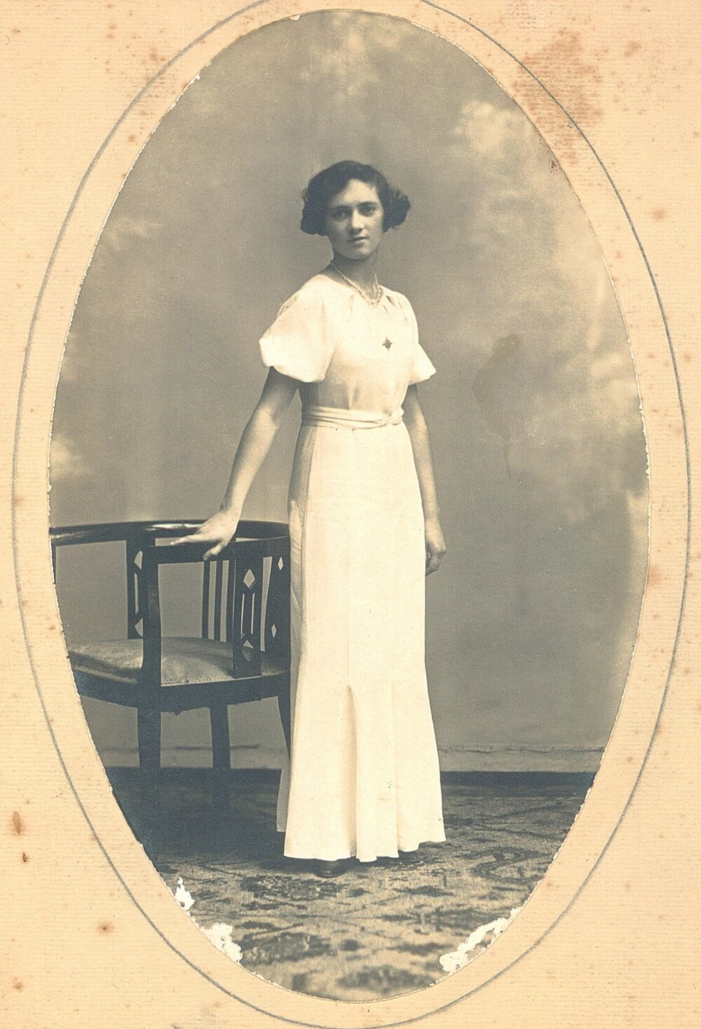 Photographic portrait of Gladys Chance in long white dress with star badge, c.1929