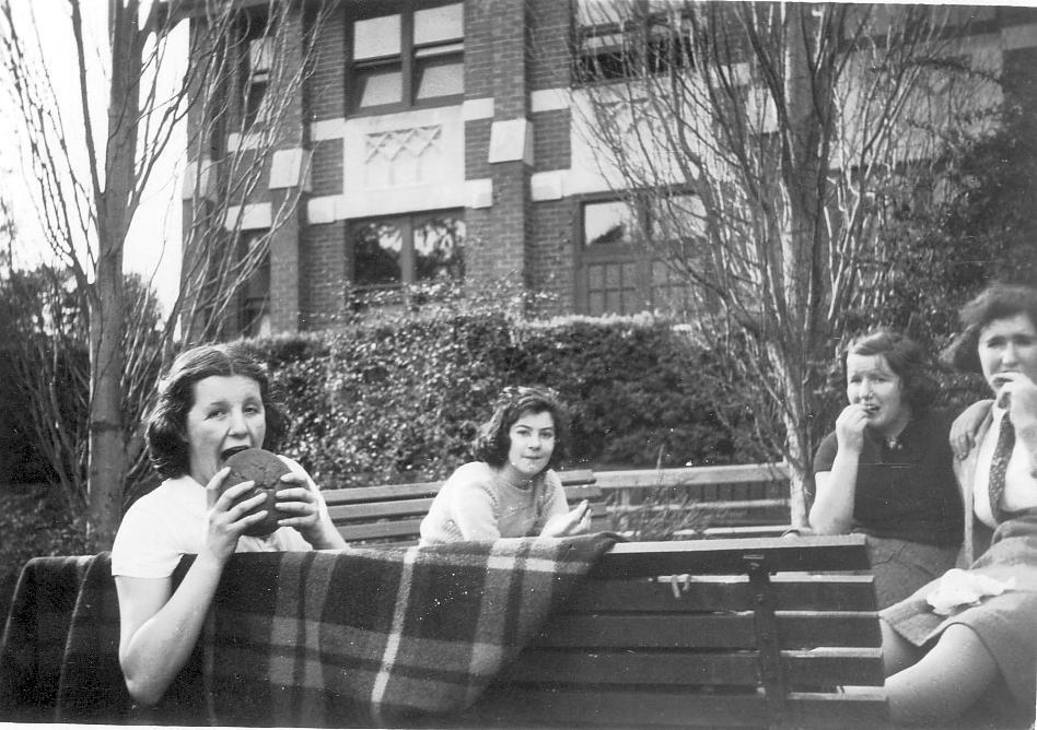 Photo of Betty Raynor, Peg Amos, [Gwen or Margaret?] Sims seated on bench near Fitchett Hall, c.1941