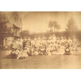 Group of Students and some staff in front gardens, possibly before an outing, 1898-1901