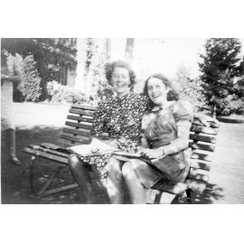 Photo of two Doreen Lancaster, Beryl Roediger in summer clothes seated on bench in front garden, c.1941