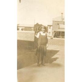 Photo of student standing in school grounds - likely 'quad' area - c.1923