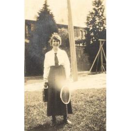 Photo of Winnie Woodmason at MLC holding valise and tennis racket, c.1917