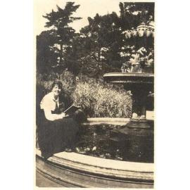 Photo of friend of Winnie Woodmason holding book, at fountain, c.1917