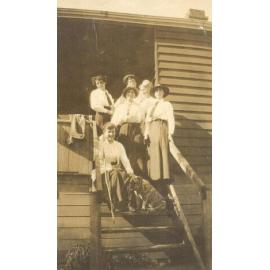 Photo of 6 students in uniform, possibly hiking trip on steps, with dog, c.1916-1917