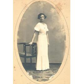 Photographic portrait of Gladys Chance in long white dress with star badge, c.1929
